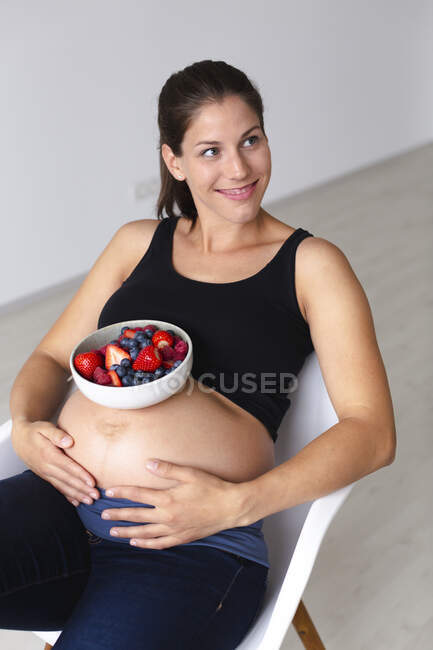 Young pregnant woman is eating different kinds of fresh fruits — Stock Photo