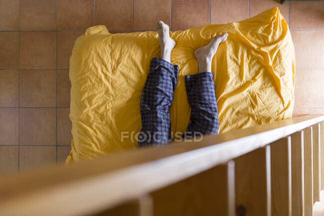 Uomo sdraiato sul letto, scala in legno — Foto stock