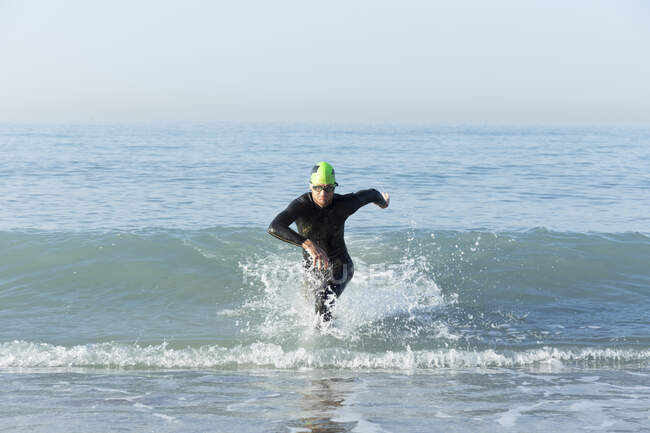 Триатлет в гидрокостюме выбежал из моря — стоковое фото