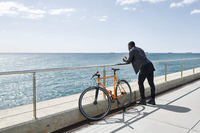 Человек с велосипедом на набережной — стоковое фото