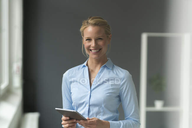 Портрет усміхненої молодої бізнес-леді з планшетом в офісі — стокове фото