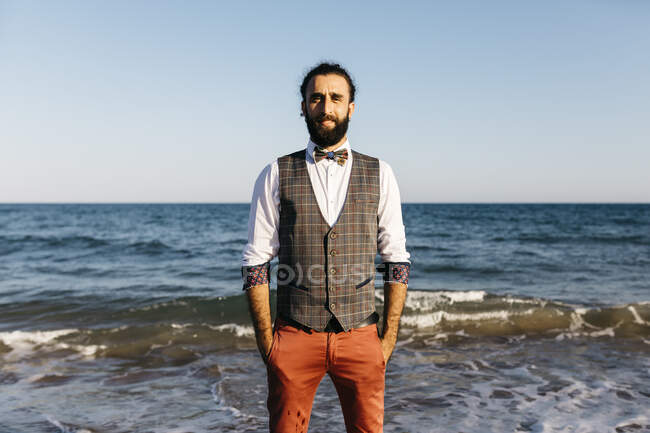 Retrato de um homem bem vestido em pé em uma praia na beira da água — Fotografia de Stock