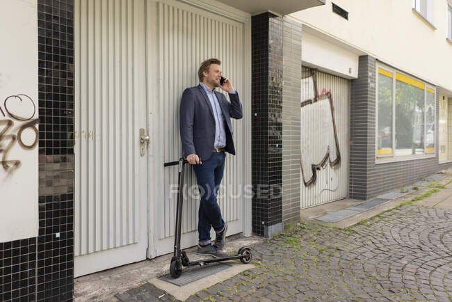 Uomo d'affari con E-Scooter al telefono — Foto stock