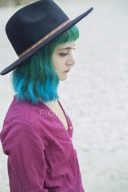 Retrato de mujer joven con el pelo teñido azul y verde y piercing en la nariz al aire libre - foto de stock