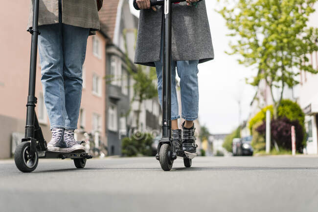 Young women riding electric scooters in the street — independence, 20 30  years - Stock Photo | #463946448