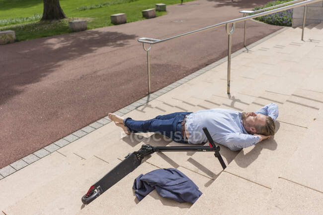 Бізнесмен з E-Scooter відпочиває босоніж по сходах. — стокове фото