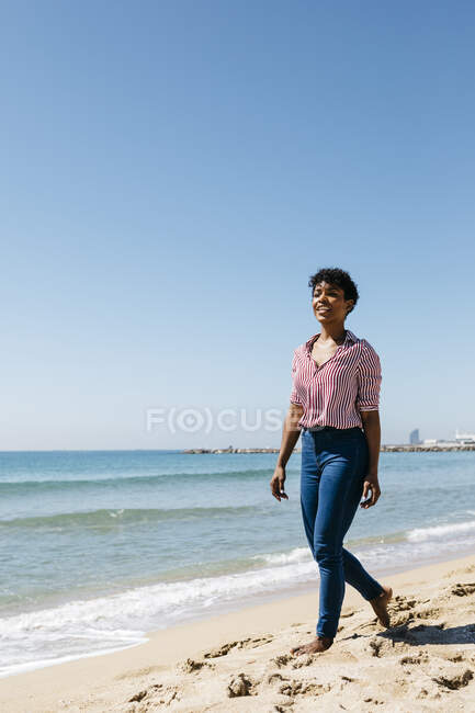 Donna che cammina sulla spiaggia, godendo il sole dopo il lavoro — Foto stock