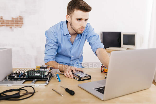 Tecnico che ripara un computer desktop, utilizzando il computer portatile — Foto stock