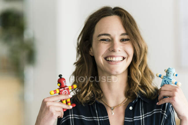 Mujer riendo sosteniendo robots de juguete masculinos y femeninos - foto de stock