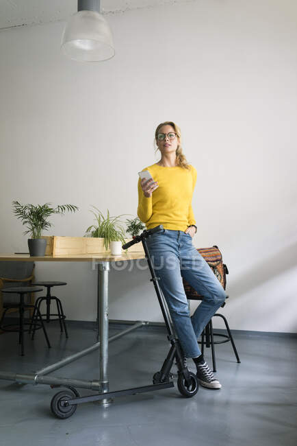 Молодая женщина с электронным скутером, отдыхает в кофейне — стоковое фото