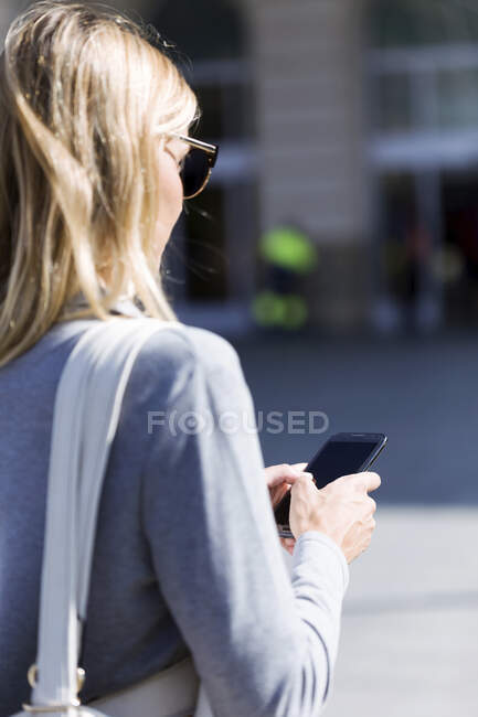 Young businesswoman texting with her mobile phone while walking - foto de stock
