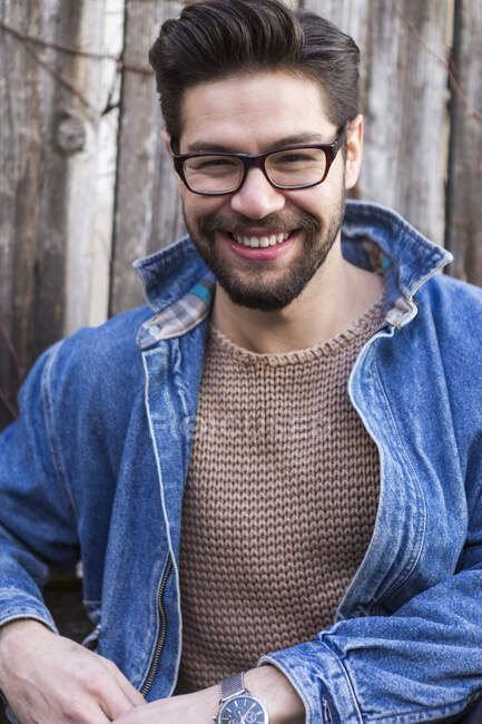 Retrato de un joven risueño con gafas y chaqueta de mezclilla - foto de stock