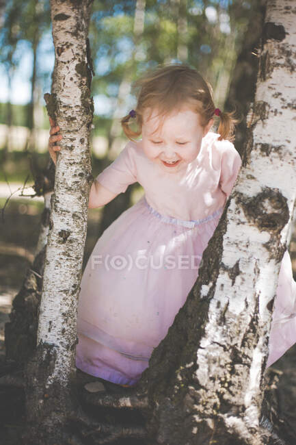 Happy little girl playing between birch trees — Stock Photo