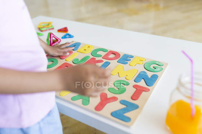 Close-up de menina jogando com alfabeto jogo de aprendizagem na mesa — Fotografia de Stock