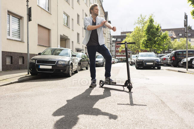 Человек, стоящий на улице с E-Scooter — стоковое фото