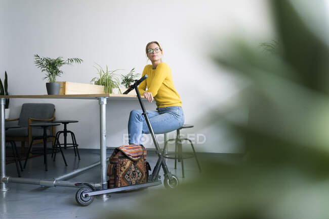 Молодая женщина с электронным скутером, отдыхает в кофейне — стоковое фото