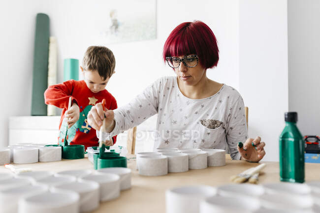 Mère et fils faisant de l'artisanat à la maison, peignant des rouleaux de carton pour faire un arbre de Noël — Photo de stock