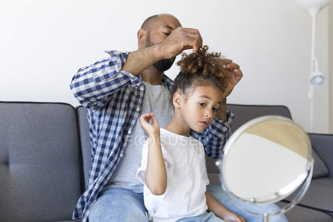 Padre che fa i capelli di figlia sul divano a casa — Foto stock