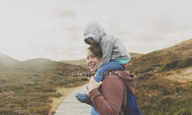 Портрет улыбающейся матери с маленькой дочкой на плечах, Силт, Германия — стоковое фото