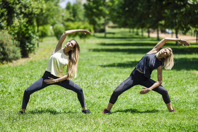 Mujer madura haciendo yoga con su hija en un parque - foto de stock