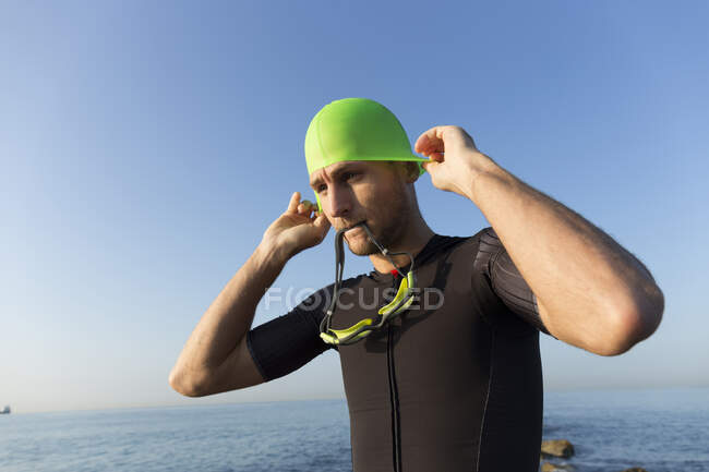 Триатлонист готовится к плаванию, надевает плавательную шапочку и очки — стоковое фото