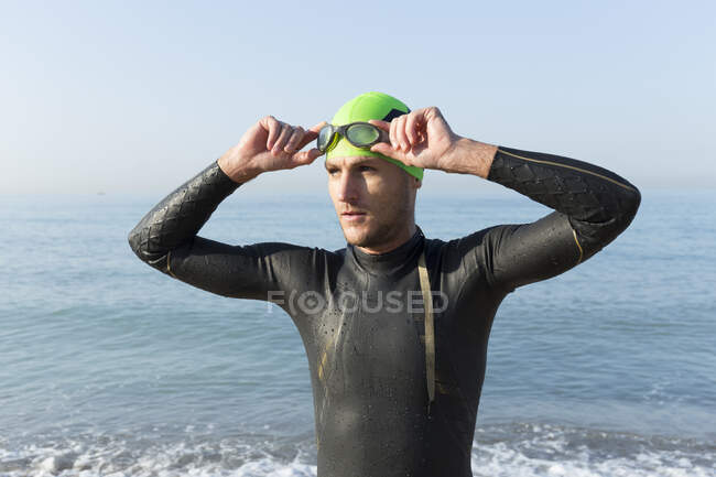 Triatleta se preparando para nadar, colocando touca de natação e óculos — Fotografia de Stock