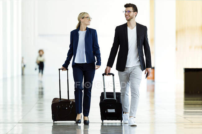 Two smiling young business partners walking at the airport — Stock Photo