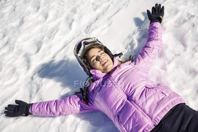 Happy woman taking a break after skiing lying on the snowy ground in Sierra Nevada, Andalusia, Spain — Stock Photo