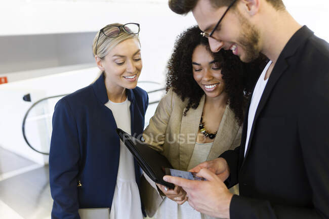 Três jovens empresários compartilhando um smartphone — Fotografia de Stock