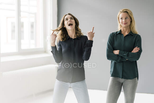 Two young businesswomen standing in bright room, imagining success — Stock Photo