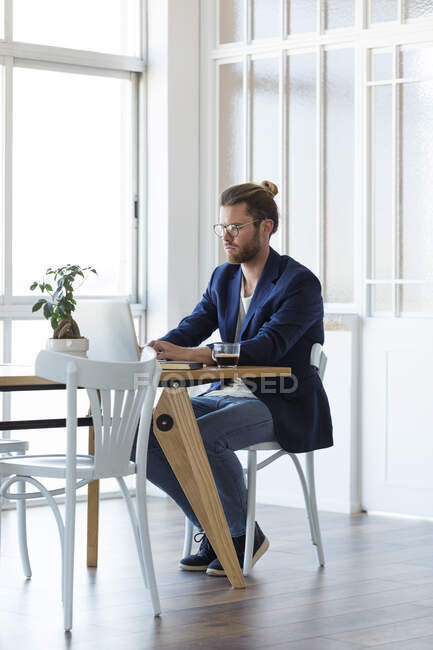 Homme d'affaires utilisant un ordinateur portable à la table dans un bureau moderne — Photo de stock