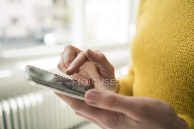 Mujer en jersey amarillo, usando smartphone - foto de stock