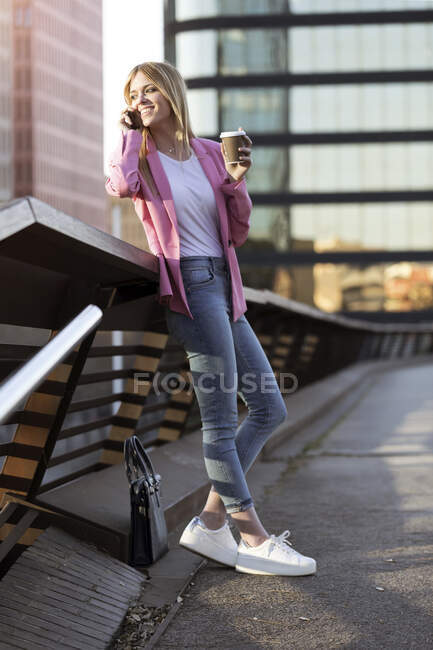 Young businesswoman using smartphone and holding coffee to go — Foto stock