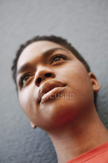 Portrait of young woman in front of grey wall, close-up — Stock Photo