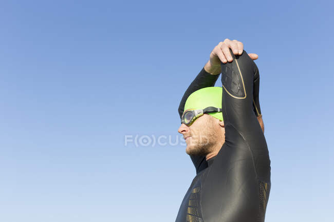 Триатлонист готовится к плаванию, растягивая руки и плечи — стоковое фото