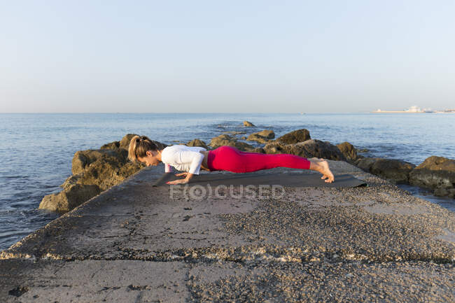 Giovane donna che pratica yoga sulla spiaggia, facendo chaturanga dhandasana — Foto stock