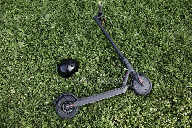 Scooter elettrico e casco sdraiato sul prato — Foto stock