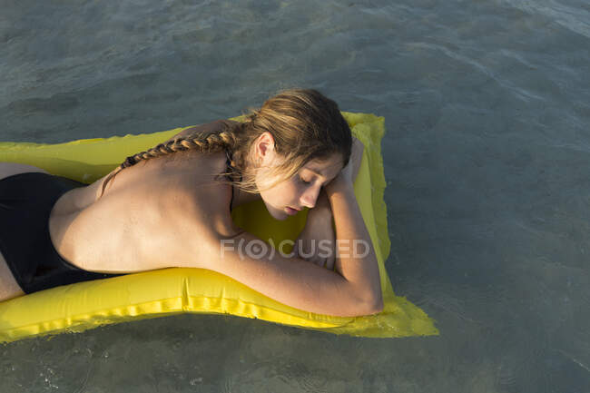Jeune femme couchée sur un lit d'air jaune et dormant — Photo de stock
