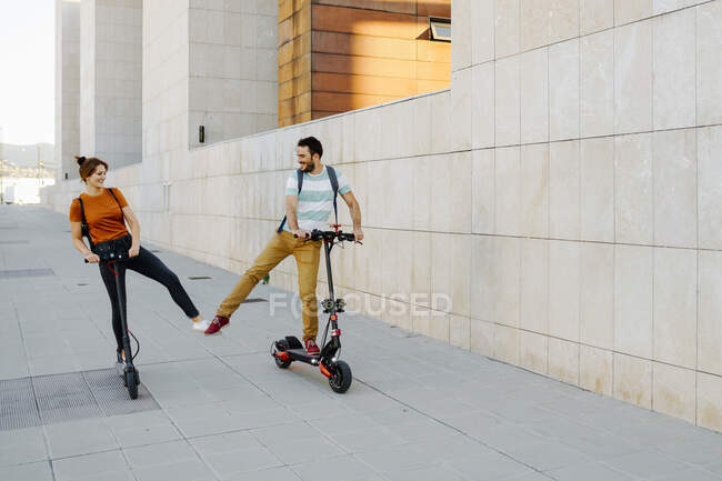 Couple heureux avec des scooters électriques dans la ville — Photo de stock
