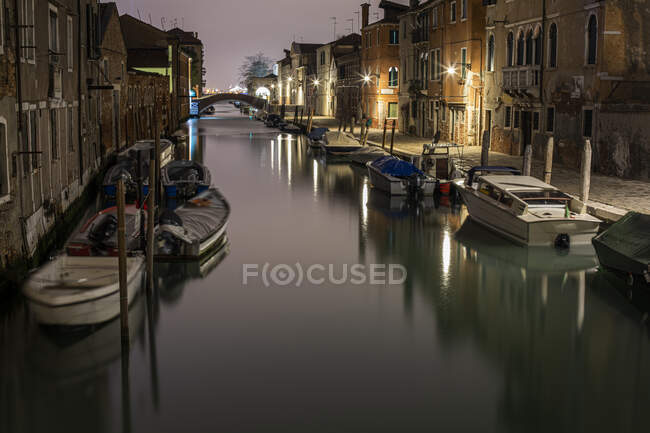 Barche ormeggiate in un canale tra edifici a Venezia di notte — Foto stock