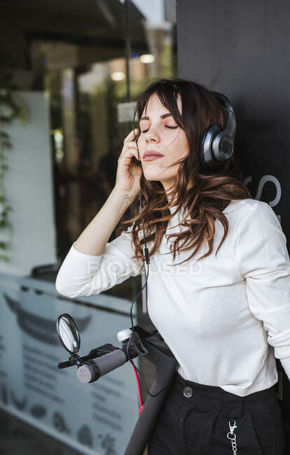 Молода жінка з E-Scooter в місті, слухати музику — стокове фото