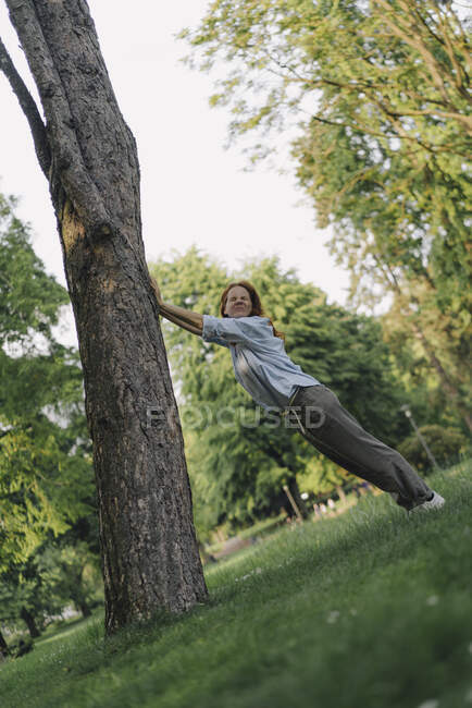 Frau im Park schiebt umgekippten Baumstamm — Stockfoto