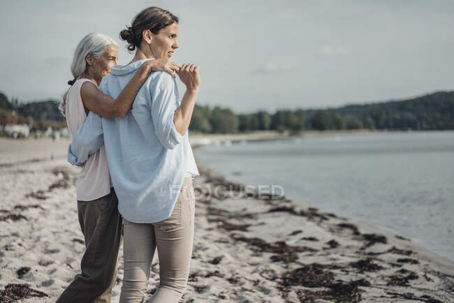 Madre e figlia trascorrono una giornata al mare, abbracciati sulla spiaggia — Foto stock