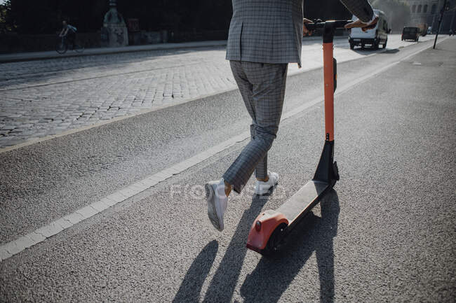 Бізнесмен ходить з електронним скутером у місті. — стокове фото