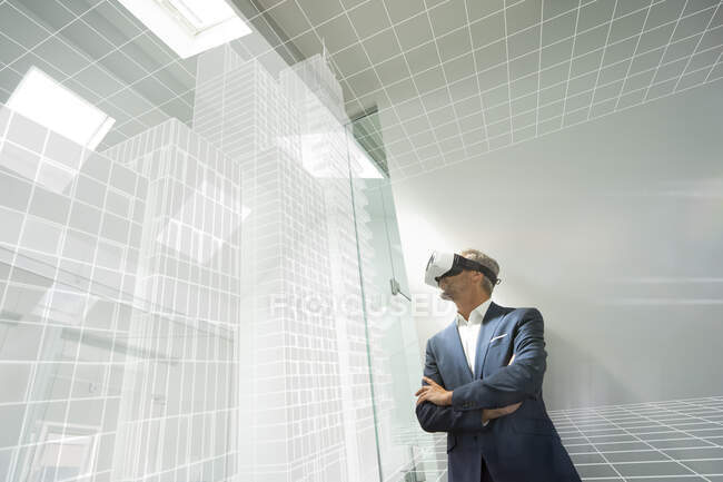 Businessman weraing VR goggles, looking at virtual architcture — Stock Photo