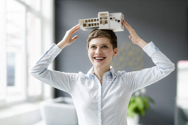 Felice donna d'affari portando modello architettonico sulla sua testa — Foto stock