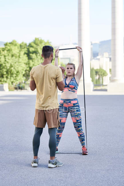 Allenatore di fitness che pratica con una giovane donna all'aperto in città — Foto stock