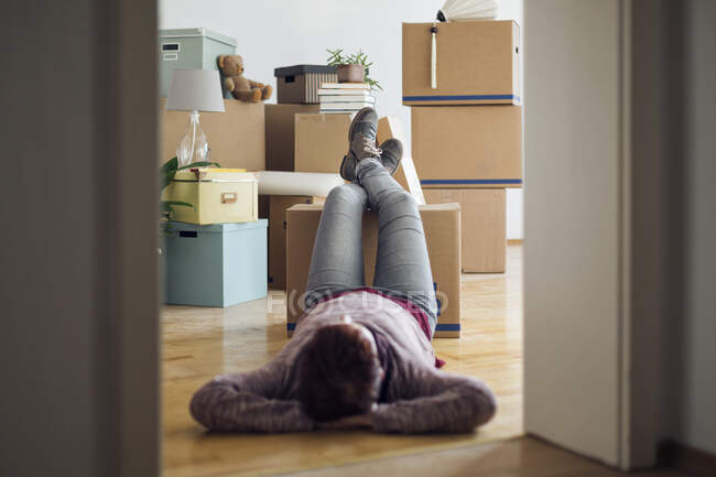 Woman relaxing surrounded by cardboard boxes in a new home — Stock Photo