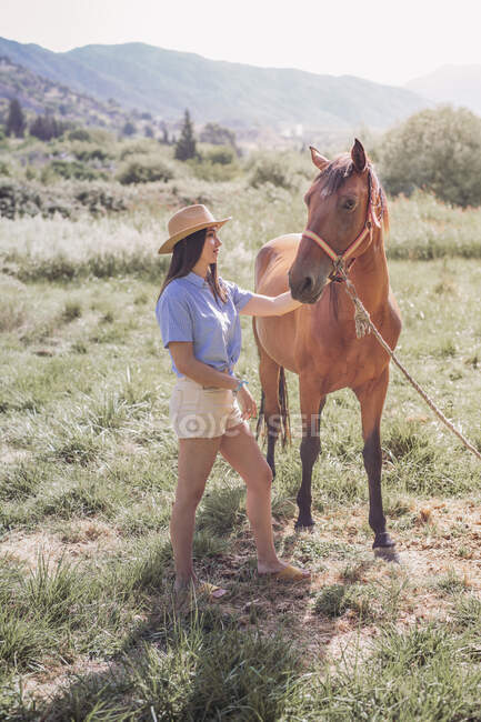 Jovem com um cavalo no prado — Fotografia de Stock