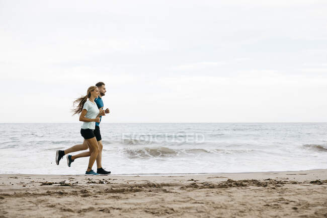 Young couple jogging on the beach — Stock Photo